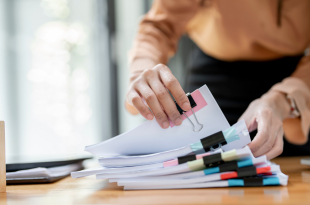 Businesswoman,Hands,Working,In,Stacks,Of,Paper,Files,For,Searching