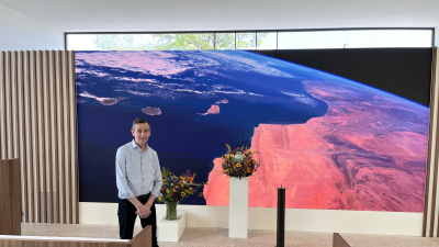 Rumo Verstappen staat bij de grote led wall in de gloednieuwe aula van Verstappen Uitvaartzorg in Beerse.
