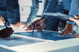 Engineer,,Scientists,And,Developers,Gathered,Around,Illuminated,Conference,Table,In
