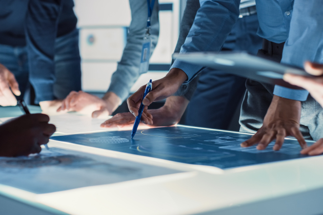 Engineer,,Scientists,And,Developers,Gathered,Around,Illuminated,Conference,Table,In