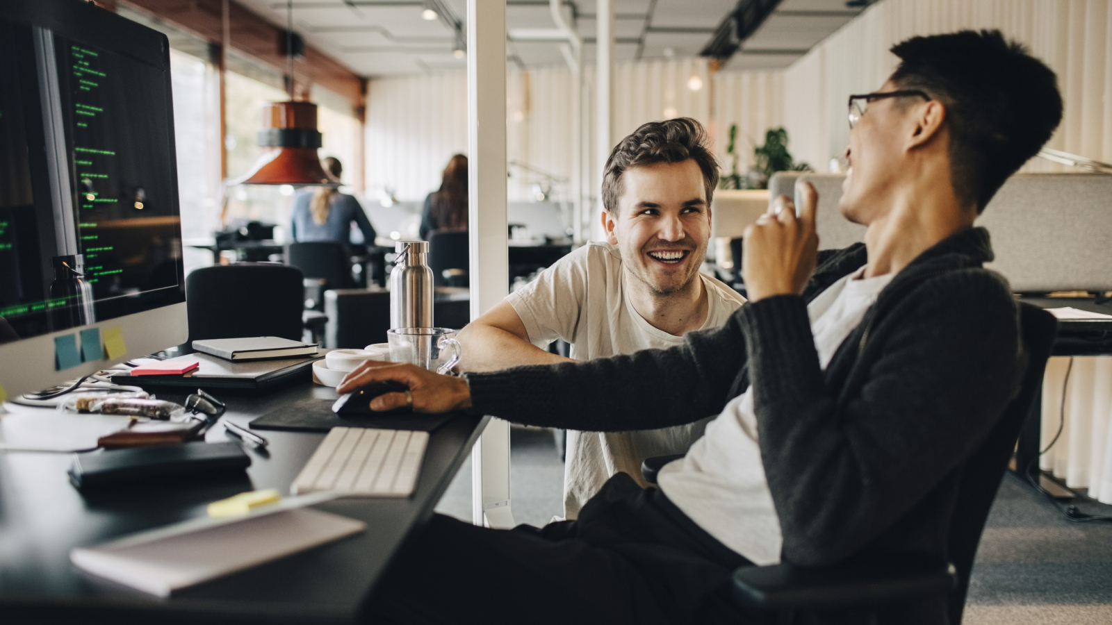 Happy multiracial computer programmers laughing while working at tech-startup office