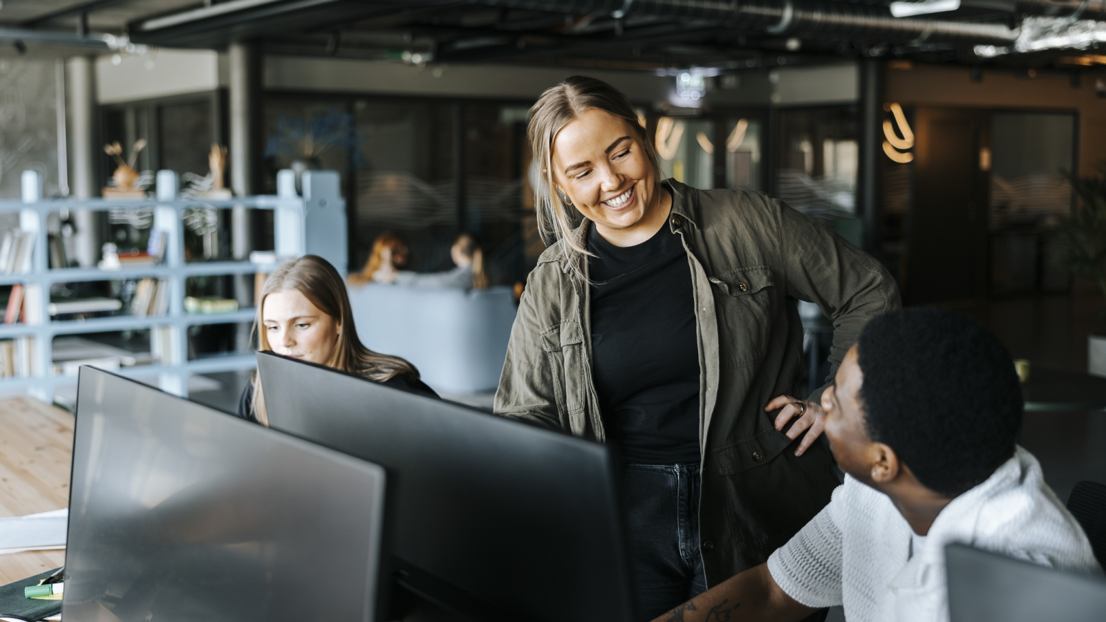 Happy male and female entrepreneurs talking in tech startup office