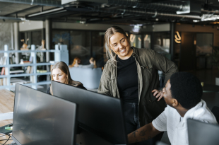 Happy male and female entrepreneurs talking in tech startup office