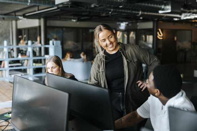 Happy male and female entrepreneurs talking in tech startup office