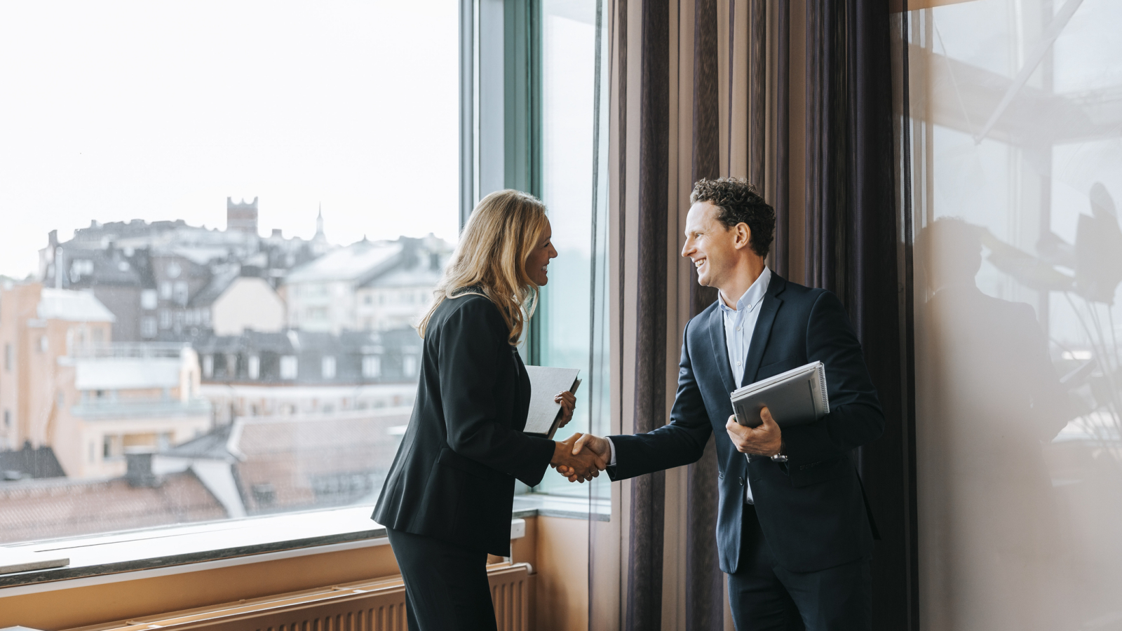 Happy male and female business professionals doing handshake at office