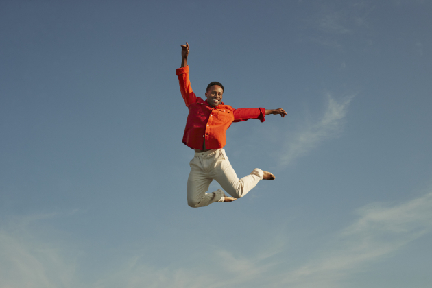Smiling man jumping with hand raised