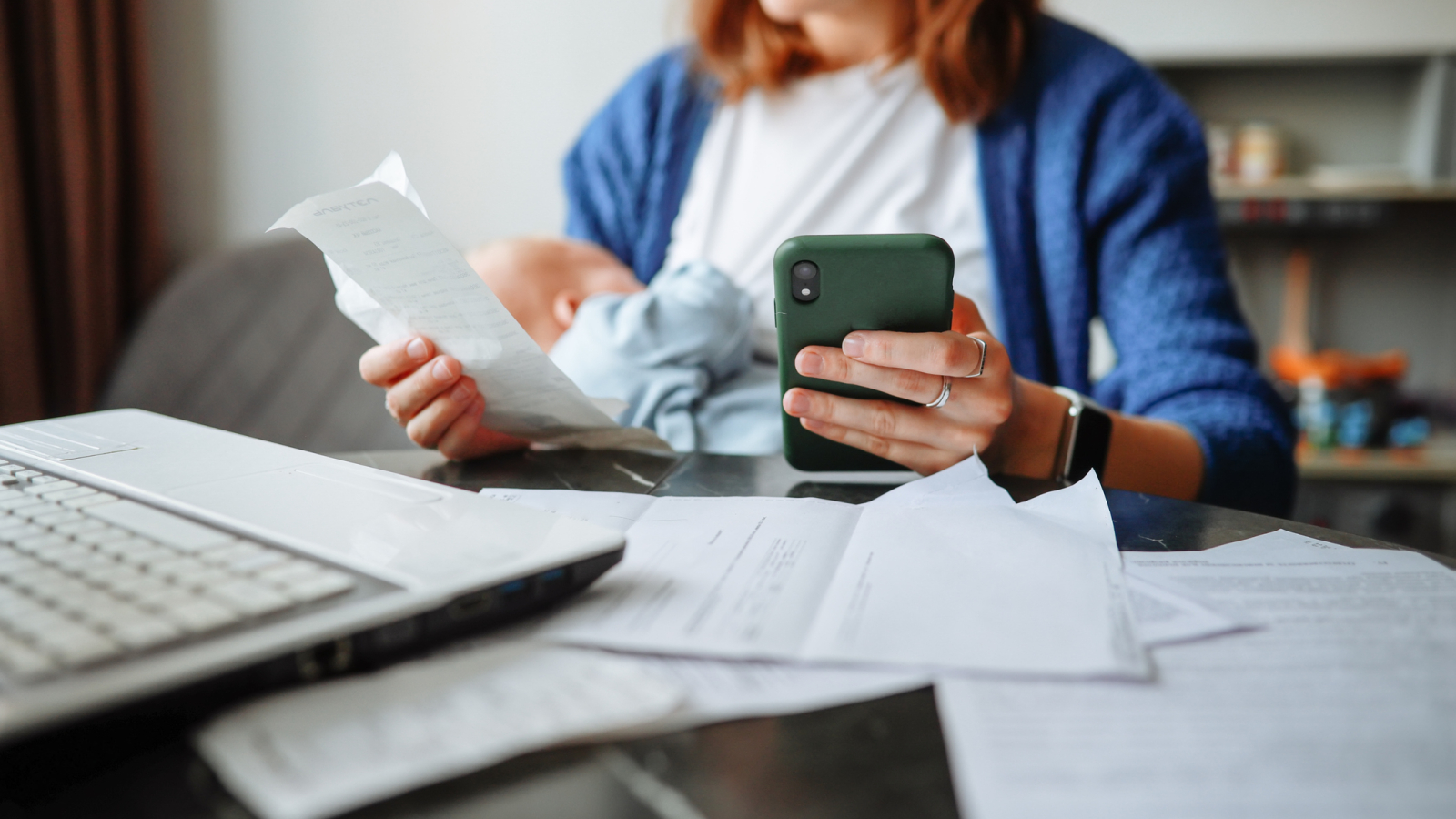 Work-life balance – middle-aged mother achieves a balance between work and personal life, dealing with finances and papers while taking care of her newborn