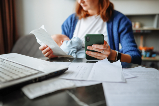 Work-life balance – middle-aged mother achieves a balance between work and personal life, dealing with finances and papers while taking care of her newborn