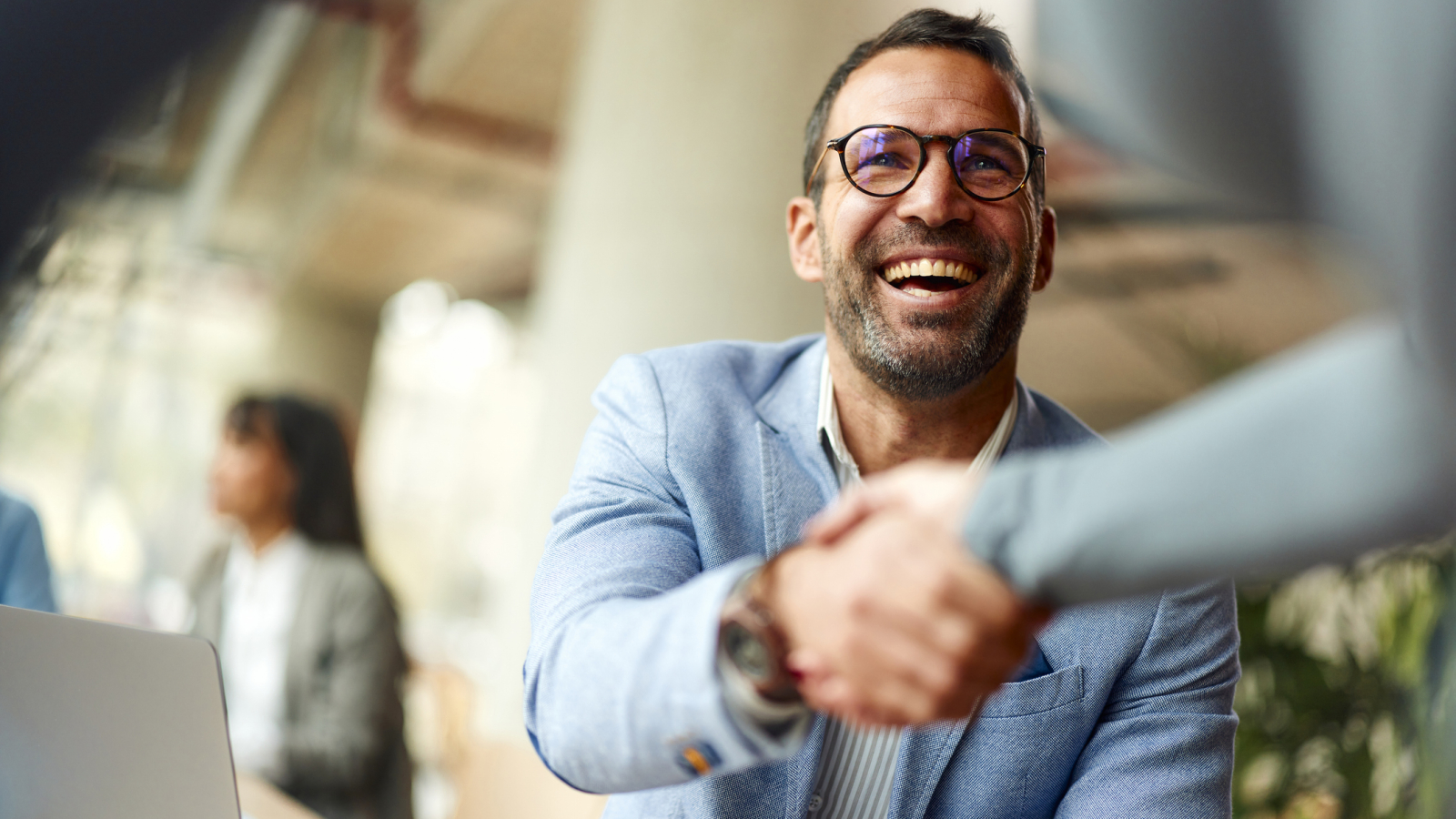 Happy businessman shaking hands with his colleague on a meeting in the office.