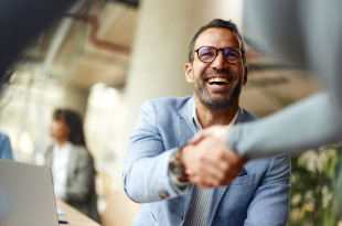Happy businessman shaking hands with his colleague on a meeting in the office.