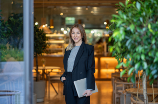 Businesswoman stands in illuminated doorway with laptop, focused on online business and marketing