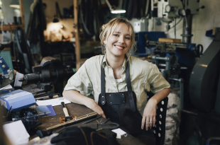 Portrait of smiling female craftsperson sitting on chair at workshop