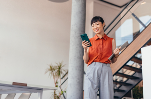 Confident Japanese Businesswoman Holding a Clipboard and using a Mobile Phone