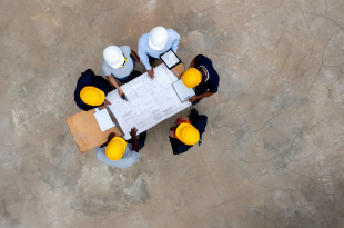 Group of construction workers in a meeting looking at a blueprint