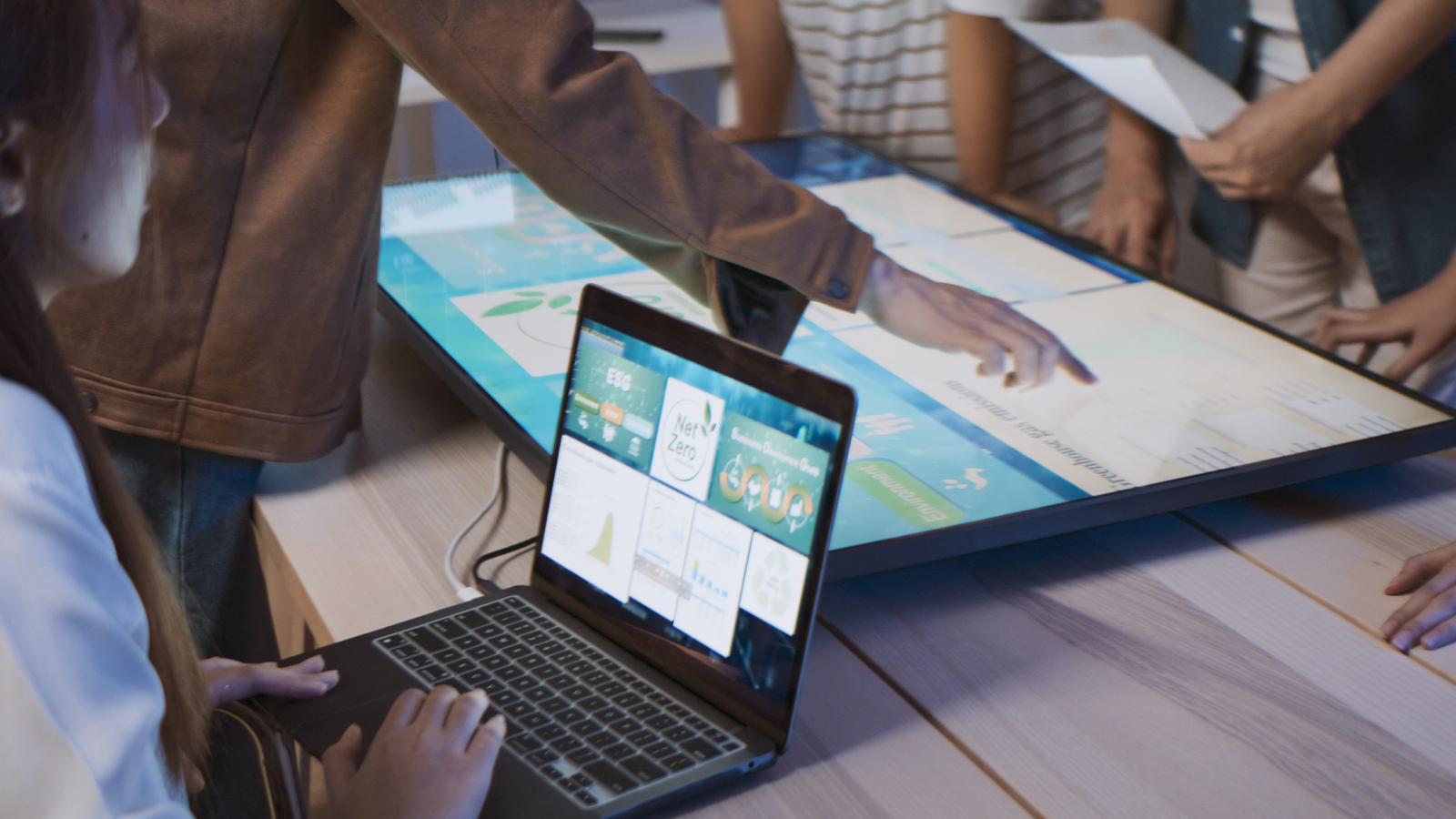 Asian business people team brainstorm meeting in sustainable office at night, using computer monitor. Discuss ESG (environmental social corporate governance) project planning. Responsible organization