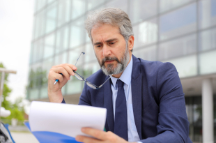 Middle-Aged Businessman Standing with Papers Outside His Office