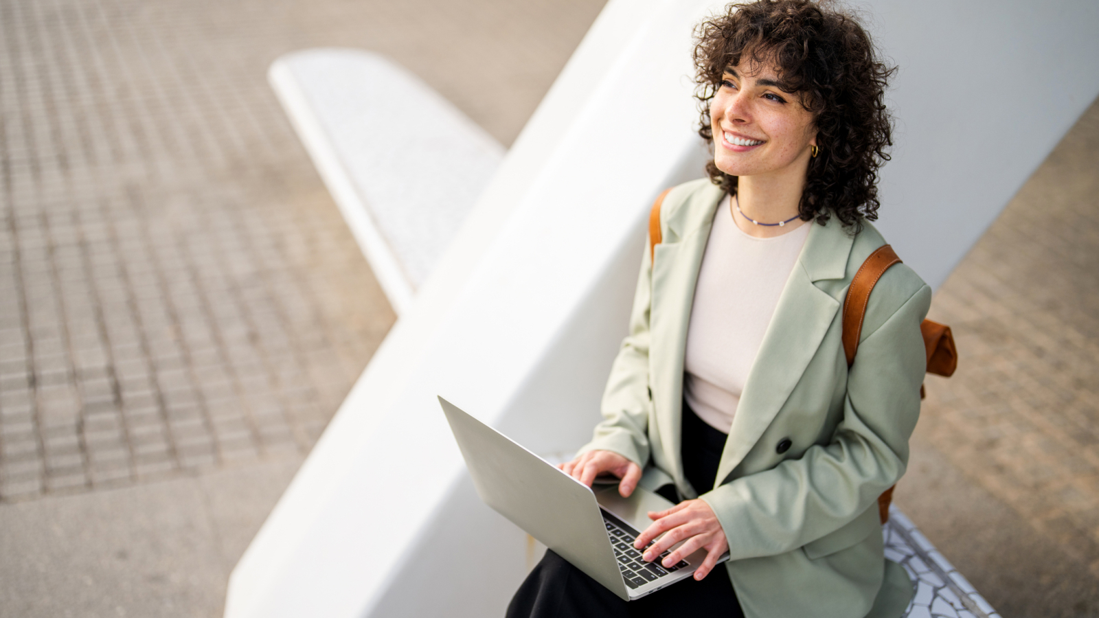 Woman sitting outdoors and using her laptop. Enjoy free WiFi and outsourcing.