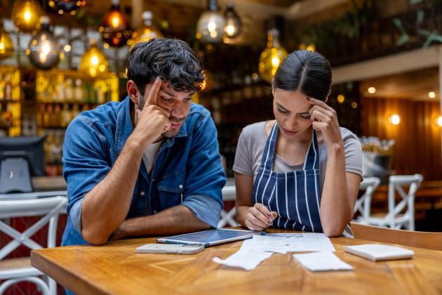 Owner and waitress doing the accountancy at a restaurant and looking worried