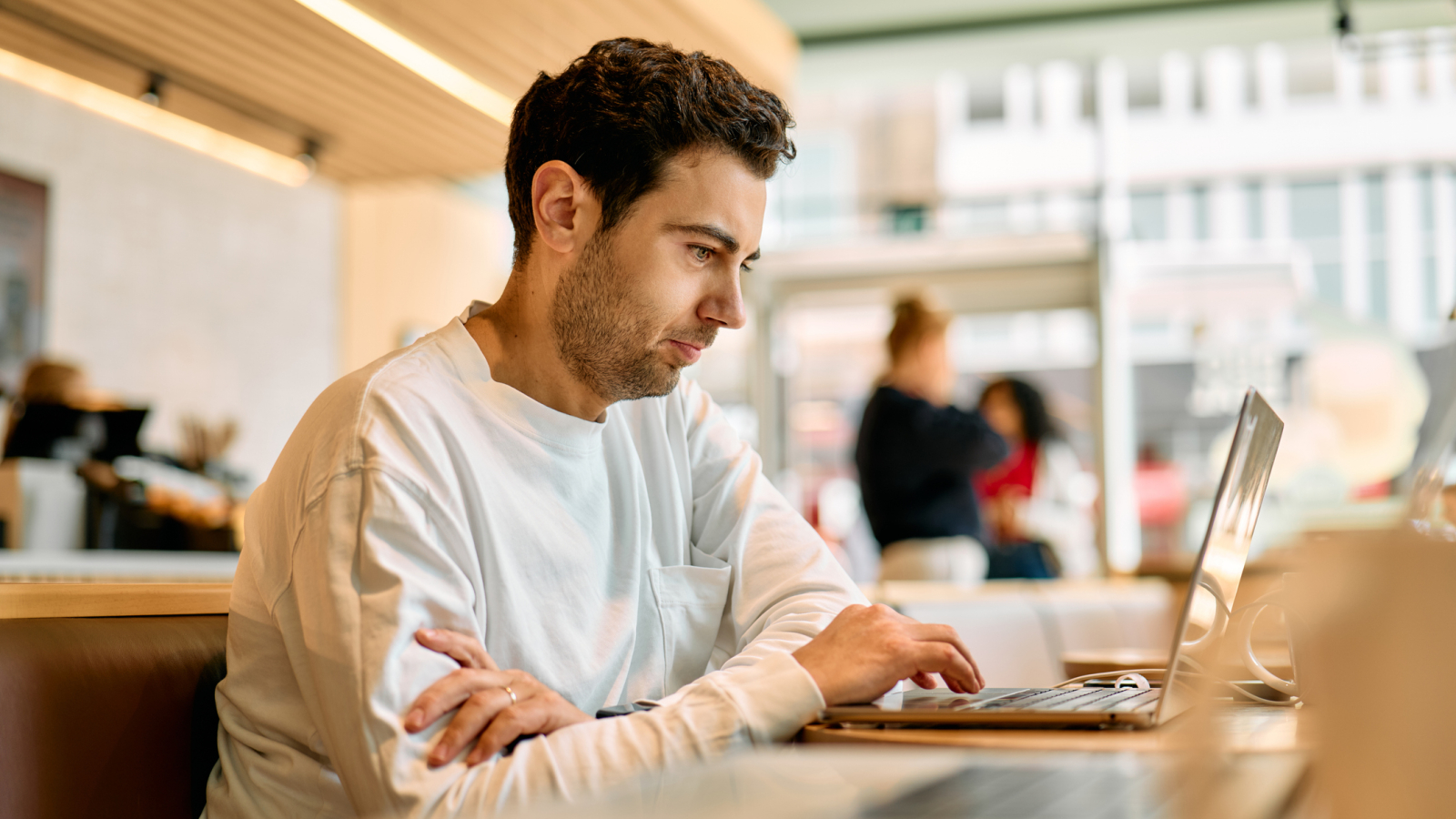 Focused young man working on laptop in modern cafe