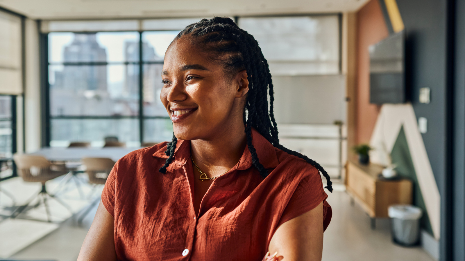 Confident computer programmer smiling and crossing arms in modern office