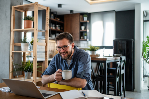 Young man working remotely from home and drinking coffee