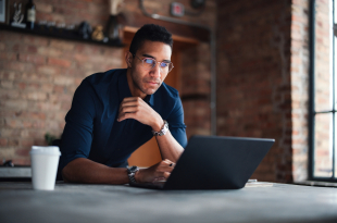 Focused Professional Working on Laptop in a Modern Brick Office Space