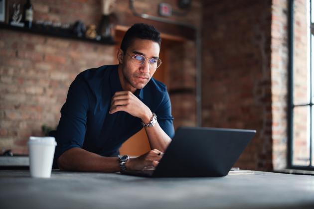 Focused Professional Working on Laptop in a Modern Brick Office Space