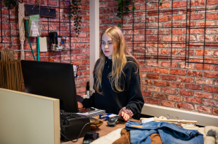 Young woman working at retail store checkout counter with a barcode scanner