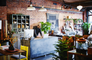 Shop owner at counter working on laptop
