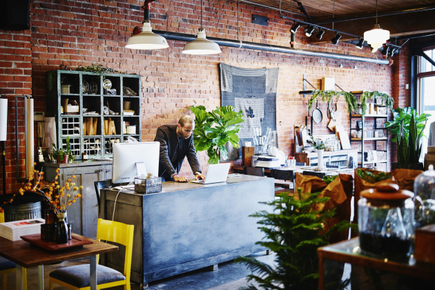 Shop owner at counter working on laptop