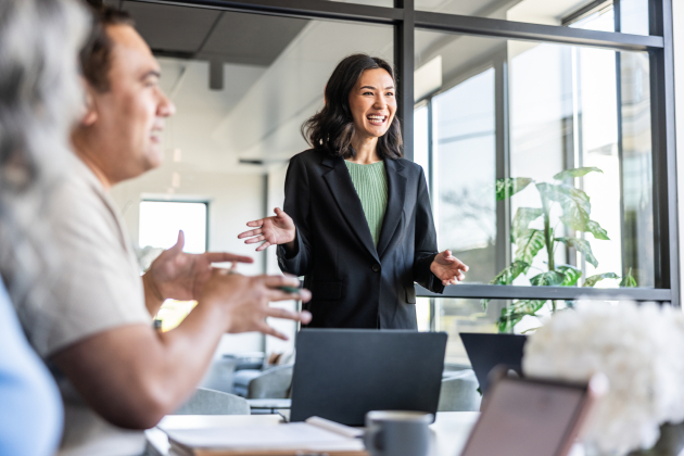 Young businesswoman speaking to colleagues in modern conference room