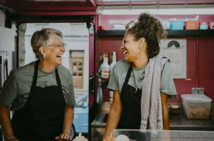 Female owner and coworker laughing in food truck kitchen