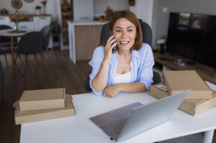 Woman managing her online business from home office talking on phone