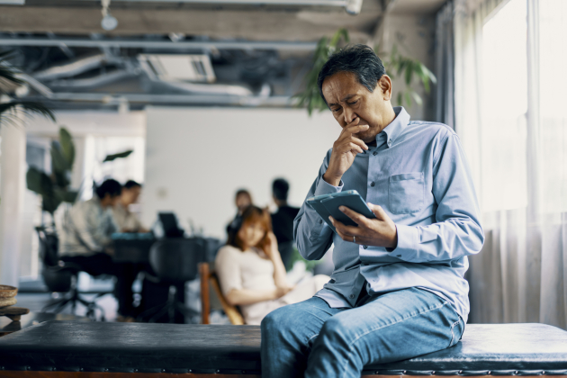 Mature man looks at tablet with a worried expression
