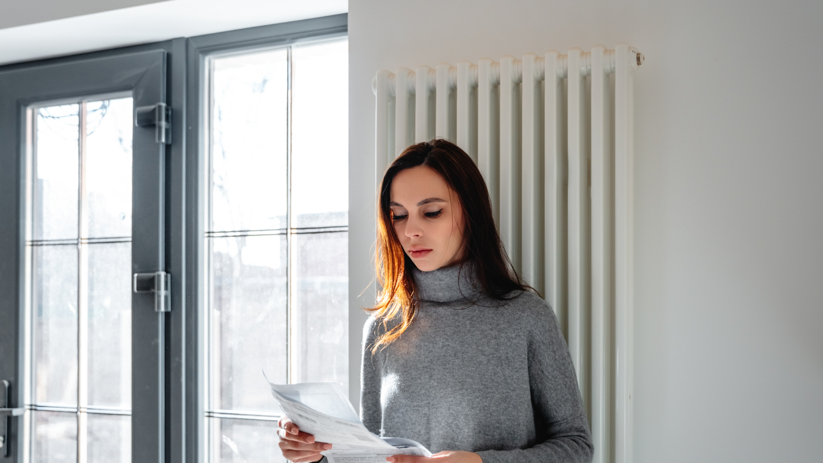 A woman looks worried while checking the electricity bill at home