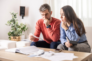A young couple checks their bank statements and mortgage contracts to determine their financial ability