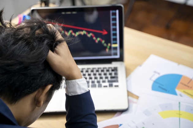 Stock trader tearing out his hair from despair, rear view