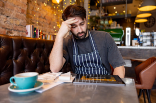 Coffee shop owner looking worried while doing the accountancy