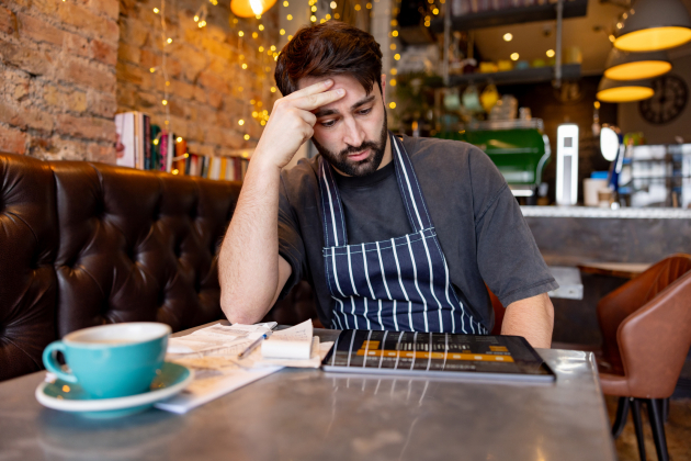 Coffee shop owner looking worried while doing the accountancy