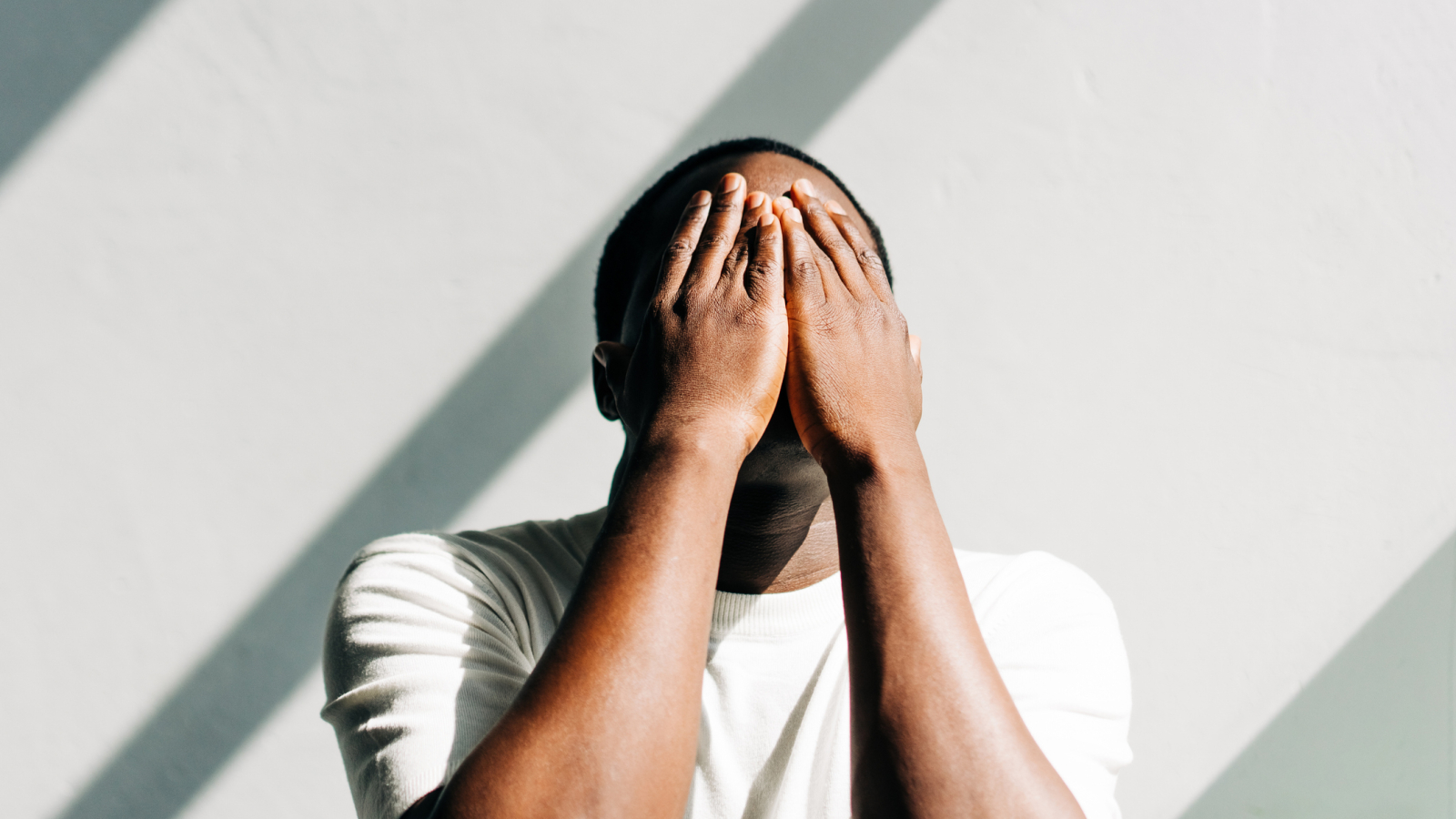 African American man tired and stressed, covered his face with his hands. Mental health, prevention of burnout and depression.