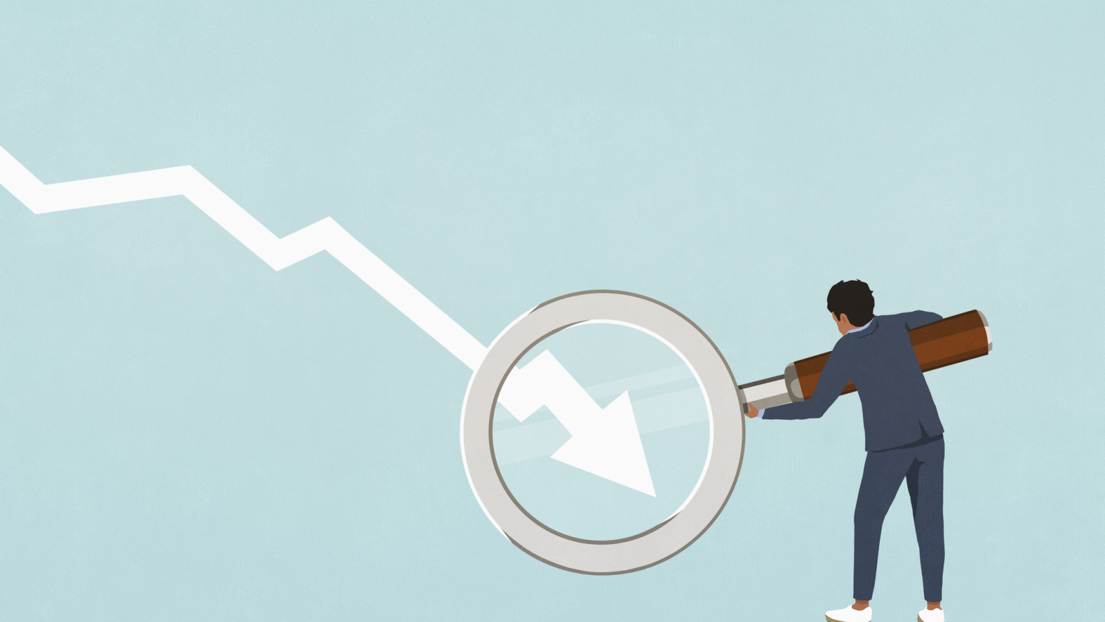 Businessman holding magnifying glass over descending chart arrow