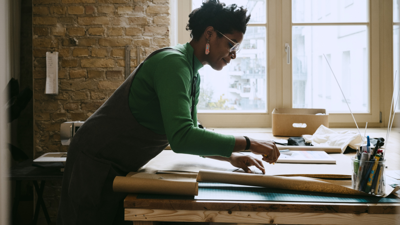 Female artist concentrating while doing craft at table in living room