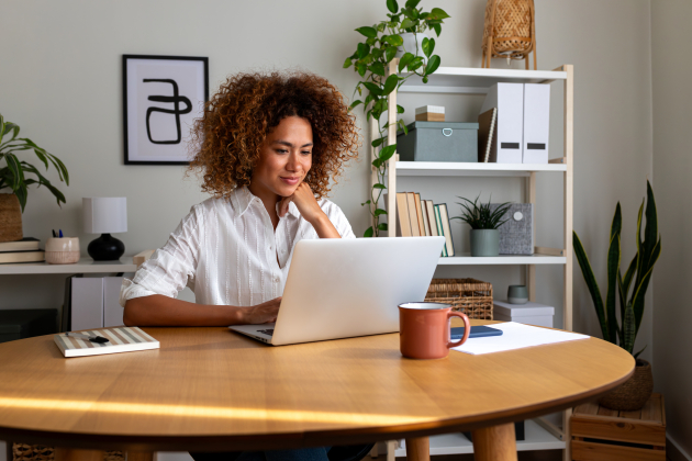Young African American woman working at home office. Happy multiracial female entrepreneur using laptop.