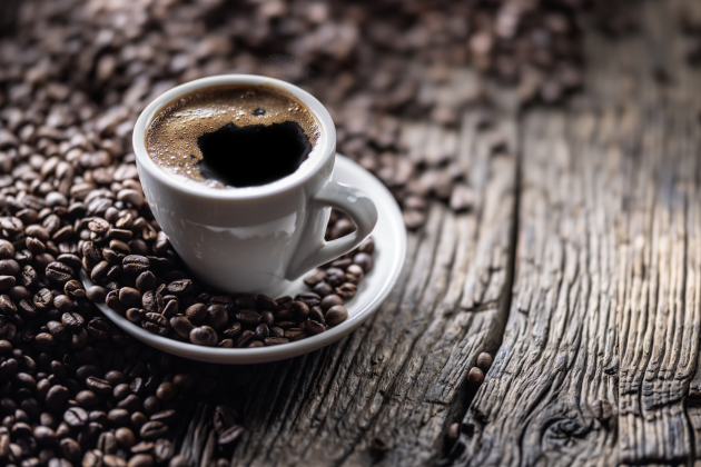 Cup of black coffee with coffee beans on old wooden table
