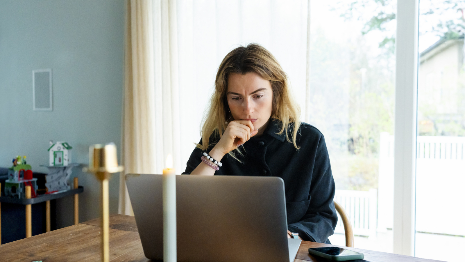 Thoughtful freelancer with hand on chin working on laptop at home office