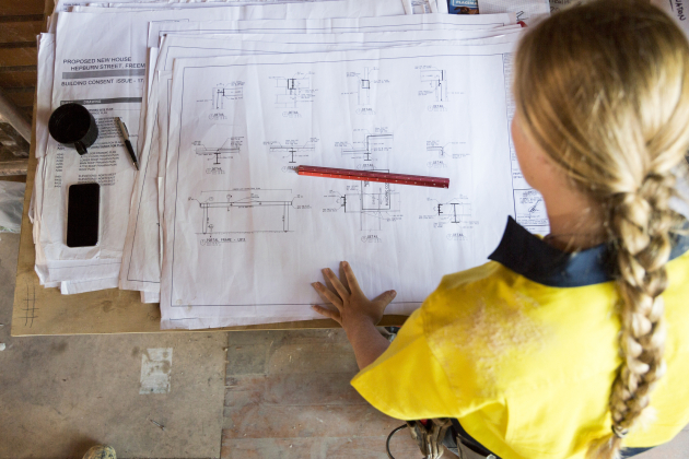 A female construction worker looks at site plans