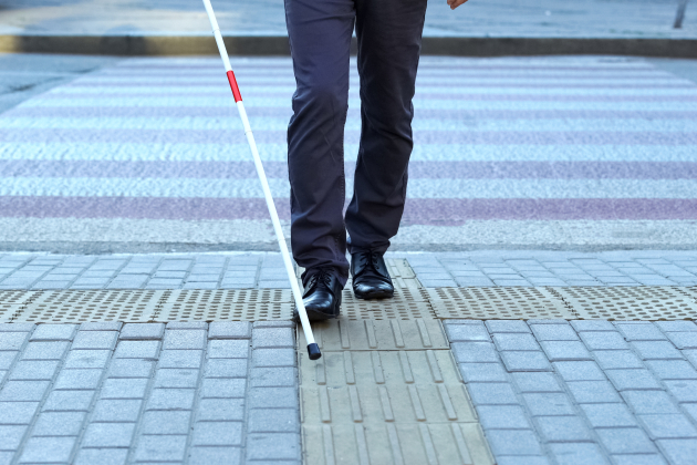 Visually impaired man using tactile tiles to navigate city, finishing crossroad