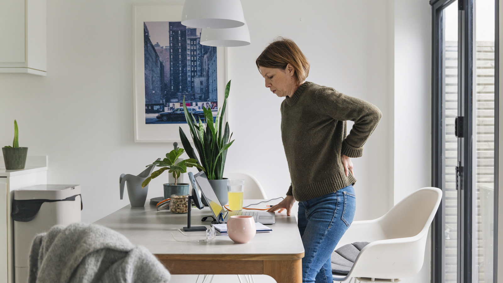 Mature woman working from home. She suffers from back pain