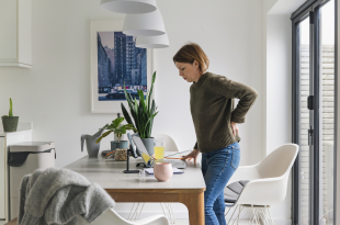 Mature woman working from home. She suffers from back pain