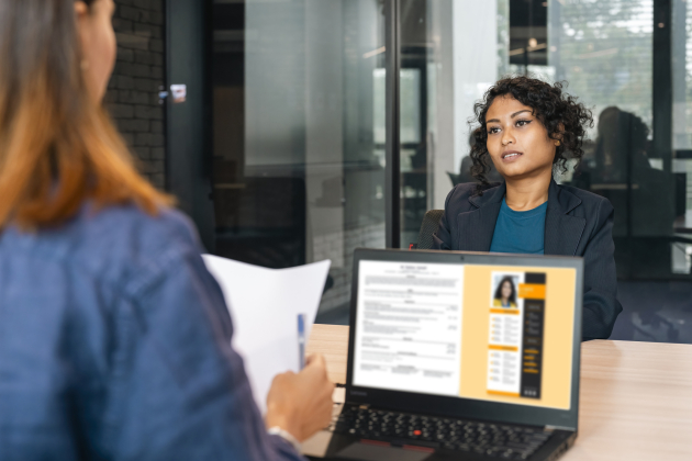 Recruiter holding candidate resume taking job interview at desk.